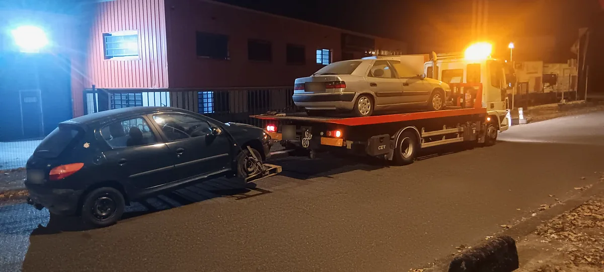 De nuit, dans une zone d'activités de Bondoufle, berline Citroën hissée sur le plateau et Peugeot 206 tenue au lève-roues