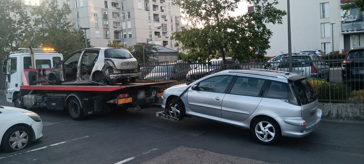 Carcasse de Renault désossée sur notre plateau et Peugeot 206 SW au lève-roues, devant une résidence à Dammarie-lès-Lys