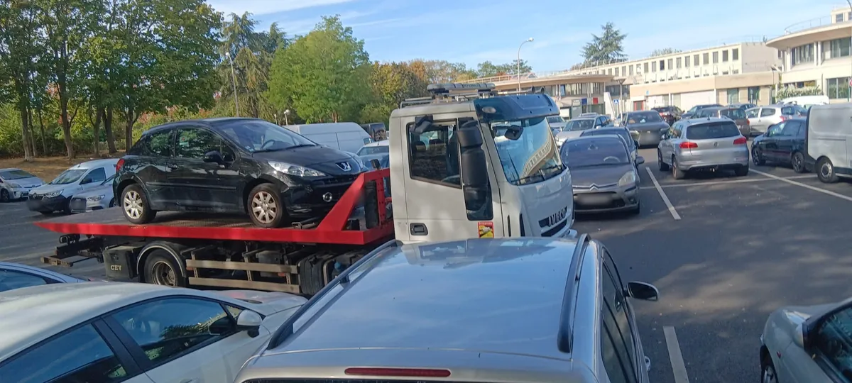 Peugeot 207 hors d'usage chargée sur le camion plateau de notre épaviste, sur un parking d'Évry-Courcouronnes (91)