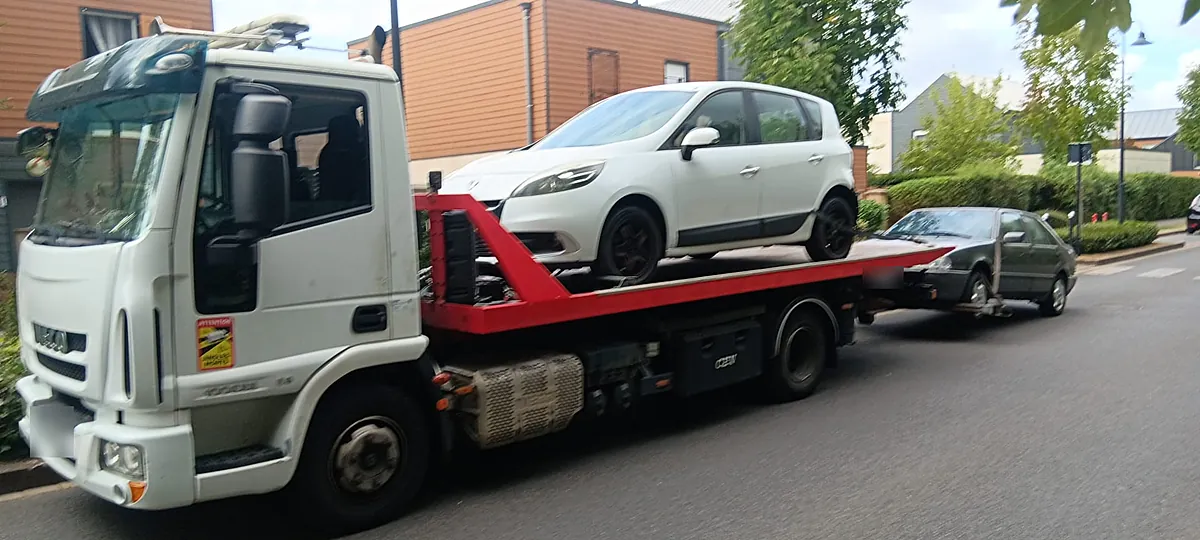 Dépanneuse plateau de notre épaviste agréé VHU à Chessy (77) : Renault Scénic chargé et vieille berline en remorque
