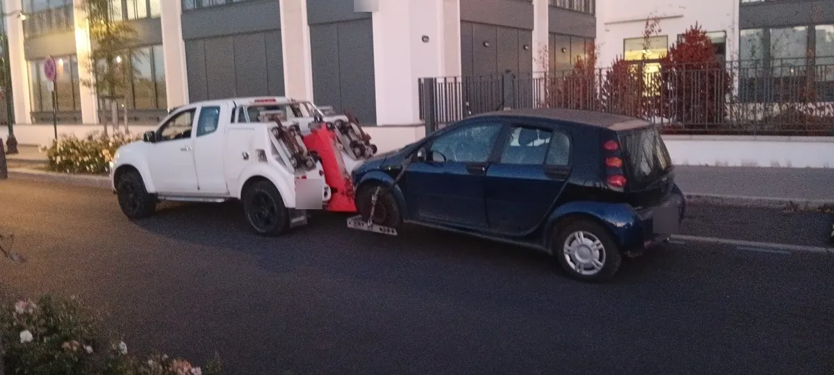 Enlèvement d'épave près de Paris : vue arrière du lève-roues de notre pick-up sous une citadine bleu foncé